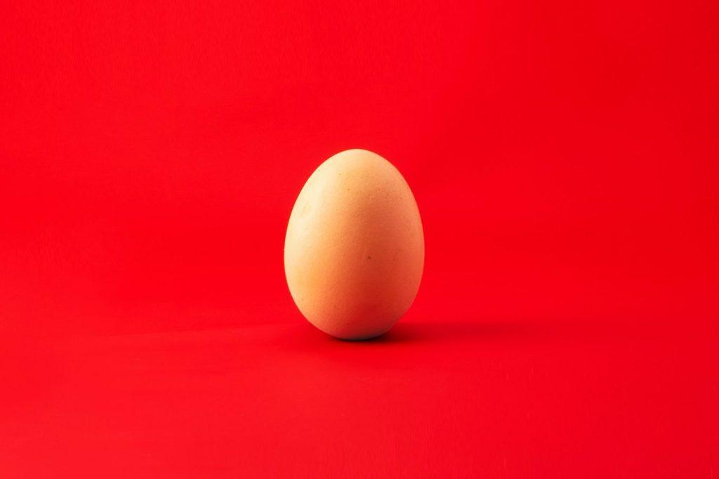 Un œuf posé sur un fond rouge vif